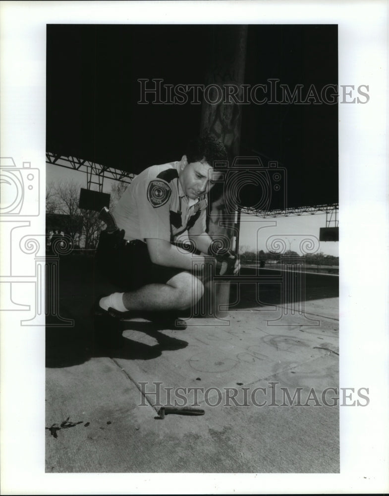 1992 Houston Bike Patrolman R. Arriaga looks at evidence at park - Historic Images