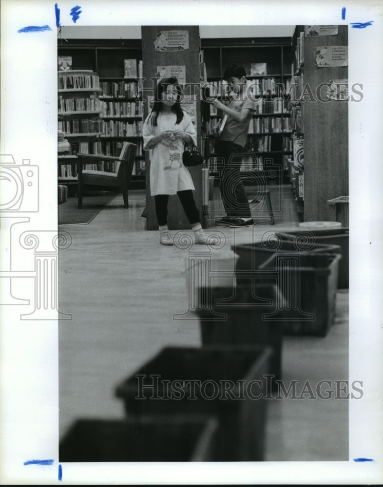 1990 Mai and Patrick Nguyen select books at Houston public libary - Historic Images