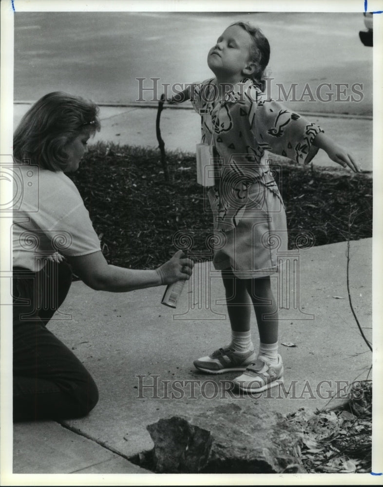 1988 Carol Huelbig sprays repellent on Patricia Raymond at Arboretum - Historic Images