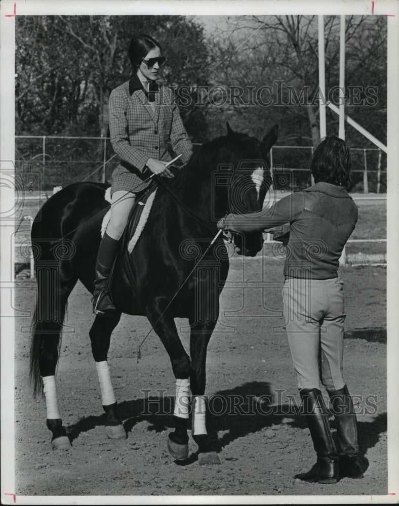 1977 Woman on horse while another holds bridle - Historic Images