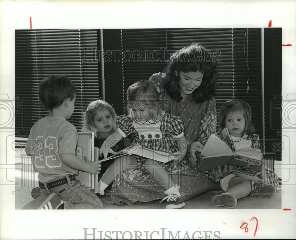 1982 Catherine Godeit and children read books at Houston library - Historic Images