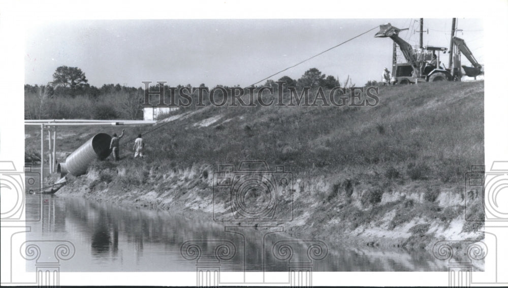 1993 Workmen use bulldozer to pull up drainage pipe from TX bayou - Historic Images