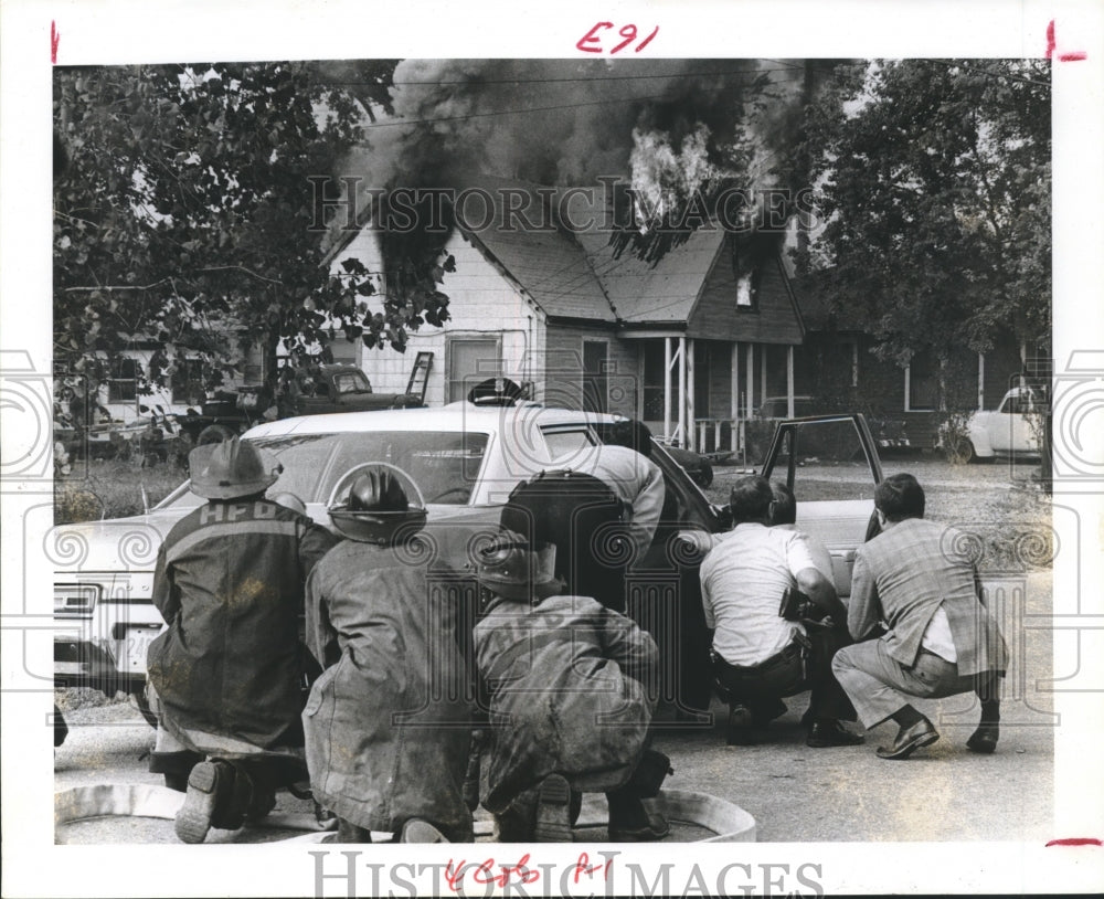 1975 Houston emergency officials duck behind car; wait for criminals - Historic Images