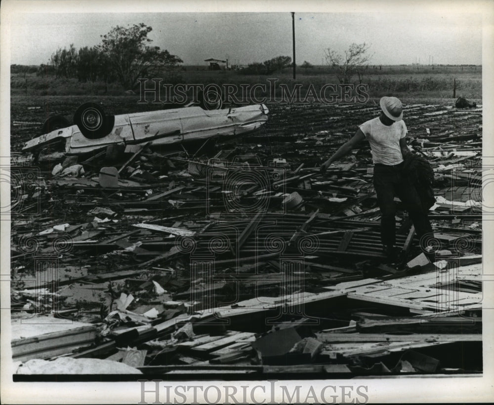 1967 Press Photo Man surveys debris and flipped car after Hurricane Beulah - Historic Images