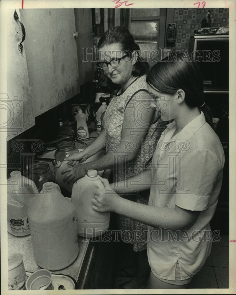 1972 Mrs. James Smith & daughter fill water bottles in Houston - Historic Images