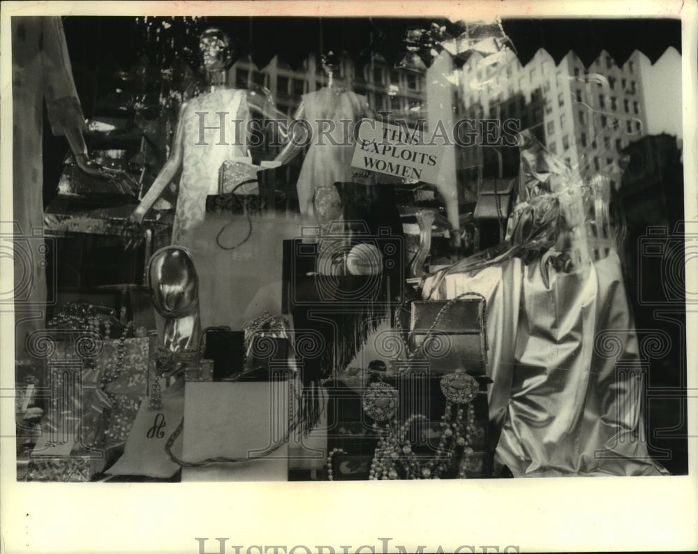 Sign in fashion store window display says "This Exploits Women" - Historic Images