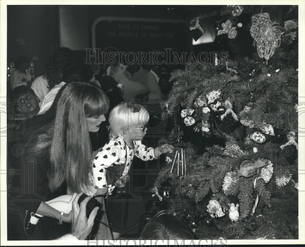1990 Press Photo Visually impaired child examines Christmas tree at HMNS, Texas - Historic Images