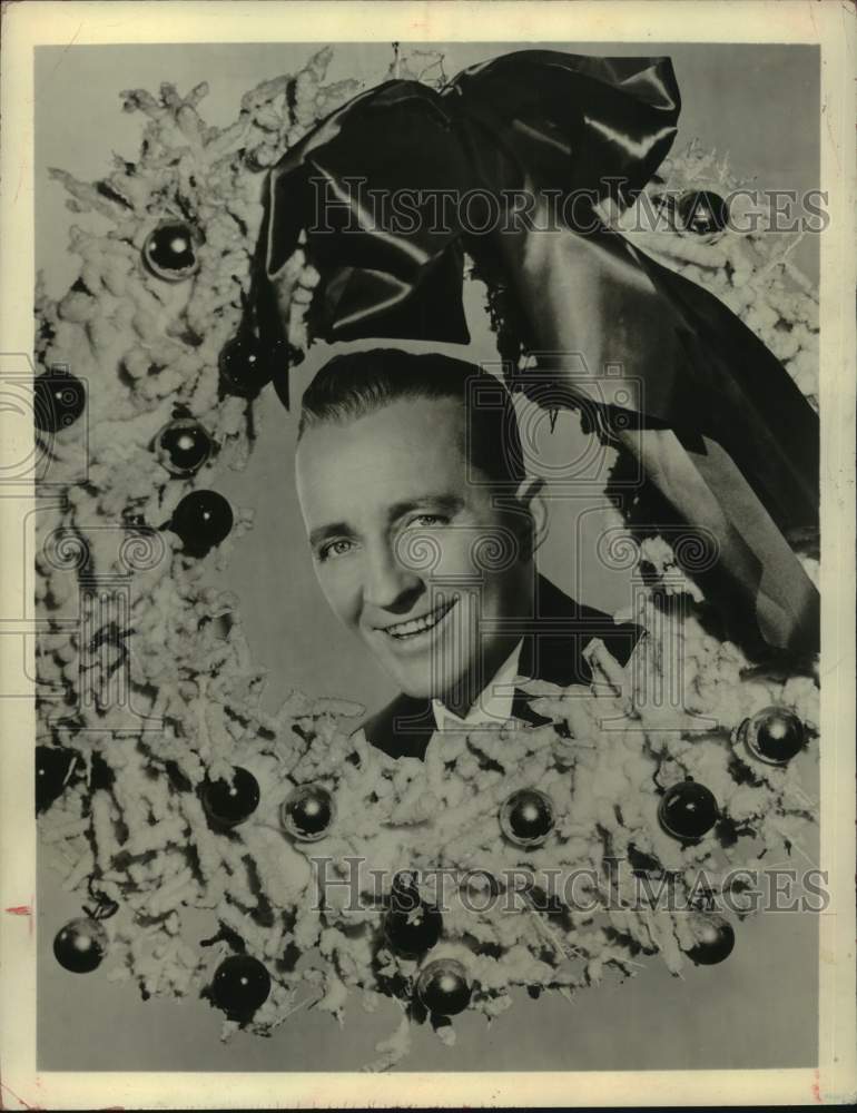 1957 Press Photo Singer Bing Crosby behind a Christmas wreath - Historic Images