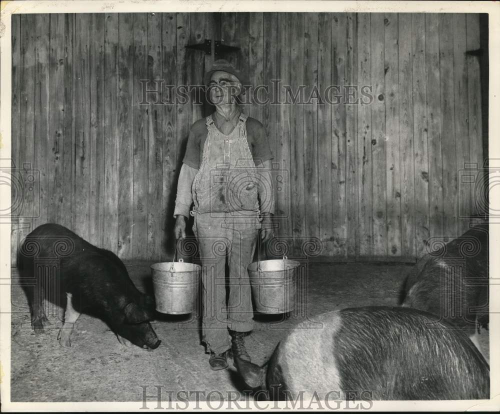 1963 Professor Howard Greene feeding hogs - Brixey, Missouri-Historic Images