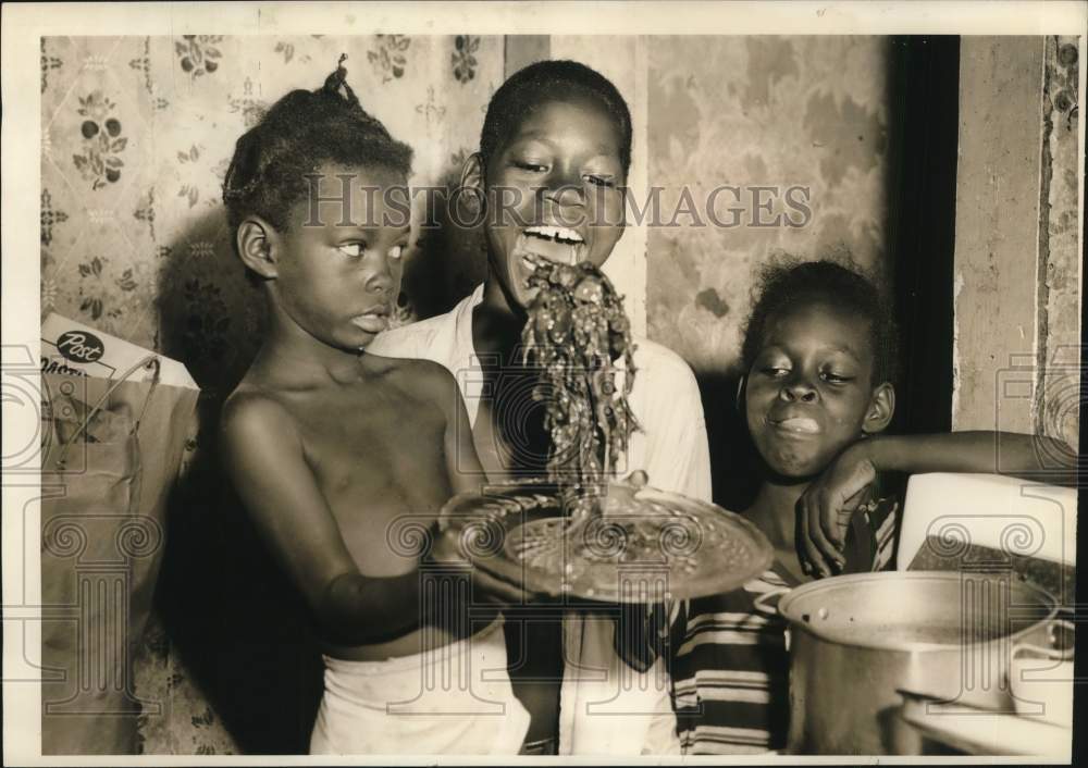 1957 Three children eat some turnip greens fresh from the garden.-Historic Images