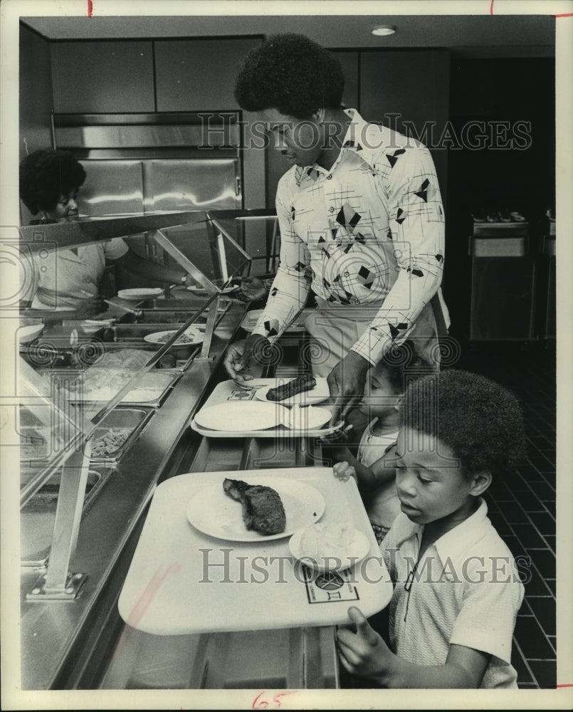 1974 Paul Gipson with his children in cafeteria food line. - Historic Images