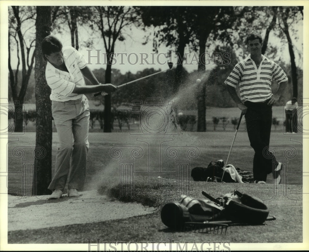 1987 Press Photo Houston-Golfer hits ball from bunker as fellow golfer watches - Historic Images