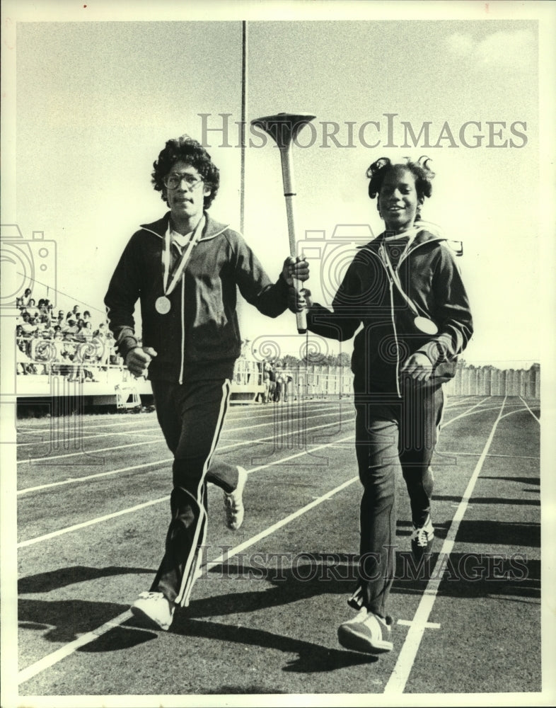 1979 Press Photo Roy Gonzales and Loretha Jefferson carry torch on track. - Historic Images