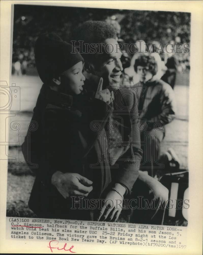 1975 Press Photo O.J. Simpson and son Jason watch game at Los Angeles Coliseum - Historic Images