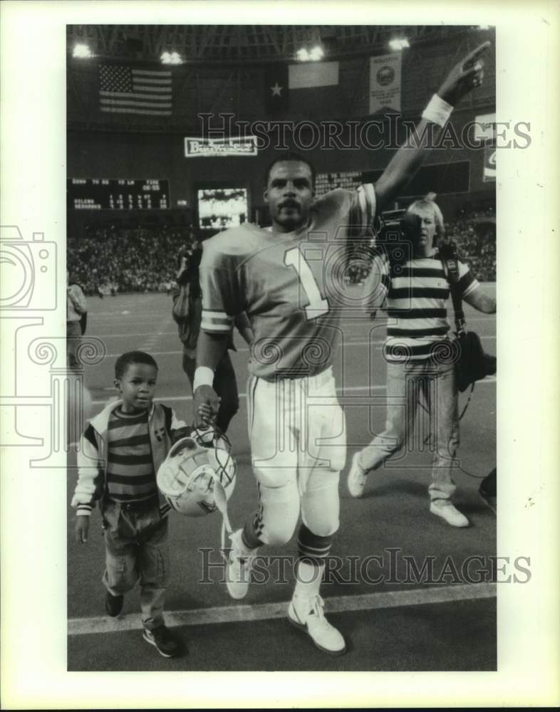 1988 Press Photo Victorious Oilers QB Warren Moon leaves the field with his son - Historic Images