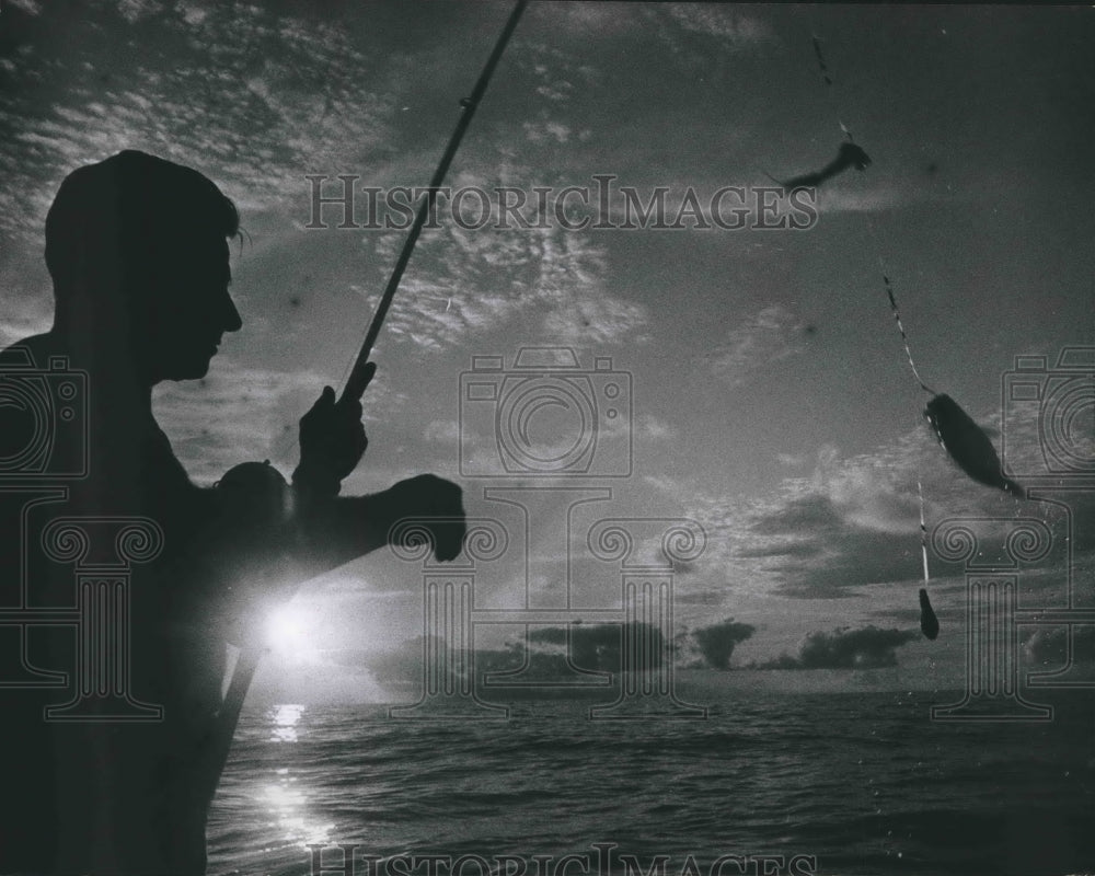 1967 Angler catches a snapper fish at sunrise - Historic Images