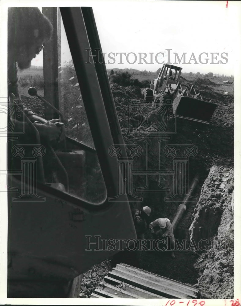 1981 construction equipment digs a ditch at Century Plaza business - Historic Images