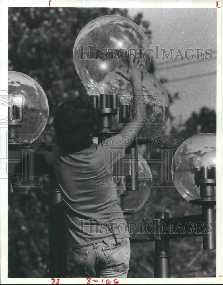 1984 Press Photo Heber Flores cleans the lights Carillon Shopping Center Houston- Historic Images