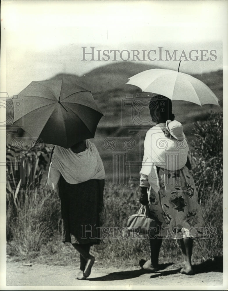 1961 Barefoot mothers with umbrella in Tananarive, Malagasy Republic - Historic Images