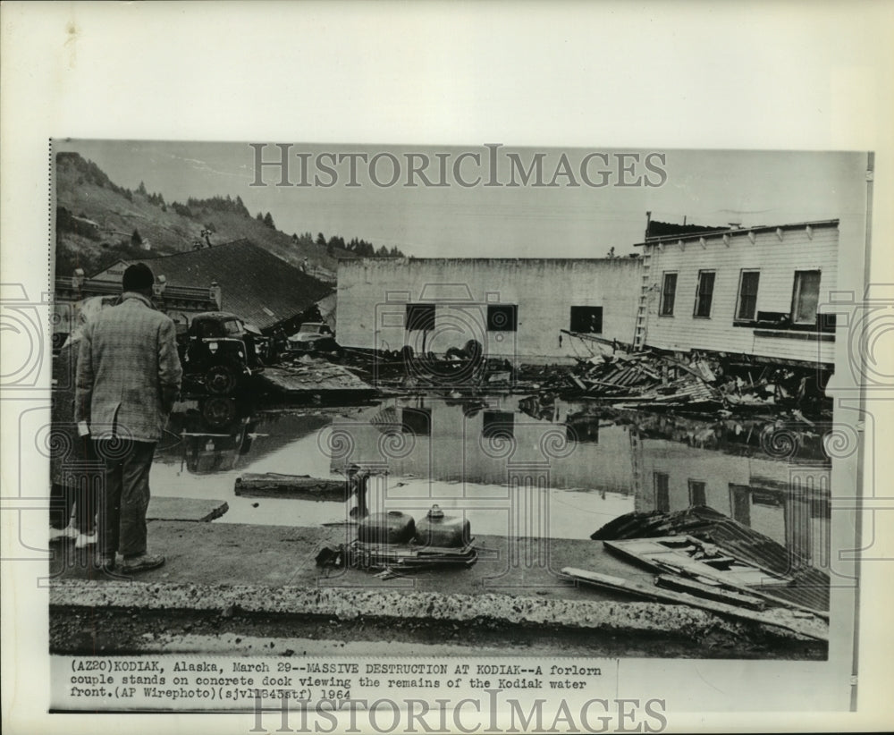 1964 couple viewing destroyed remains of Kodiak, Alaska waterfront - Historic Images