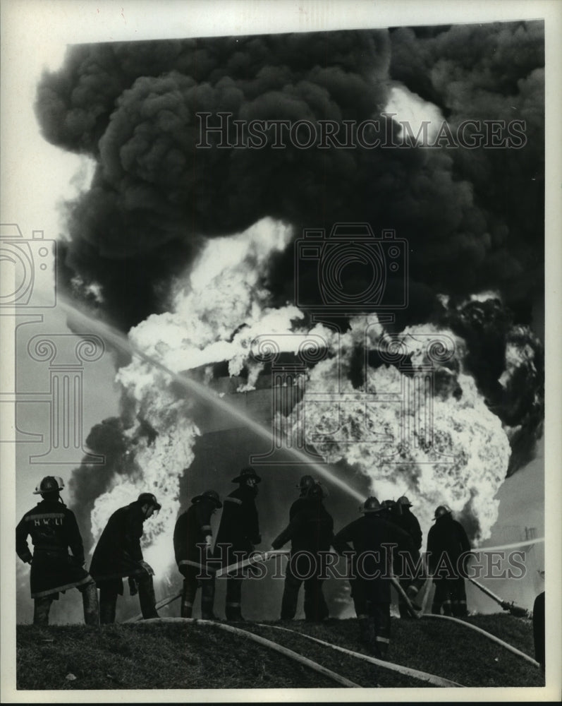1969 Fireman spraying water at Fire at Mobil Oil Corp. - Historic Images