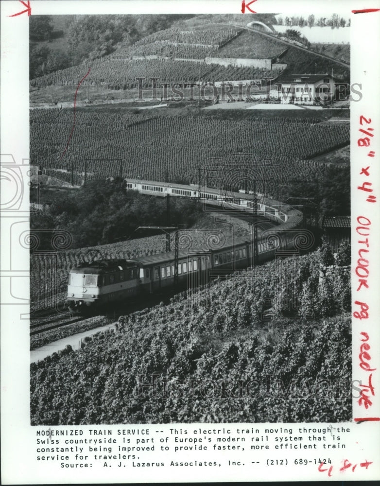 1980 Electric train moving through Swiss countryside - Historic Images