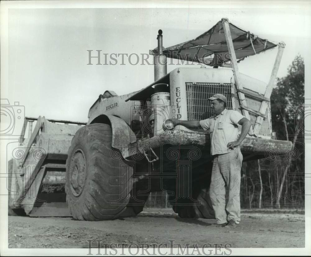 1962 Construction worker by large equipment on Texas highway site - Historic Images