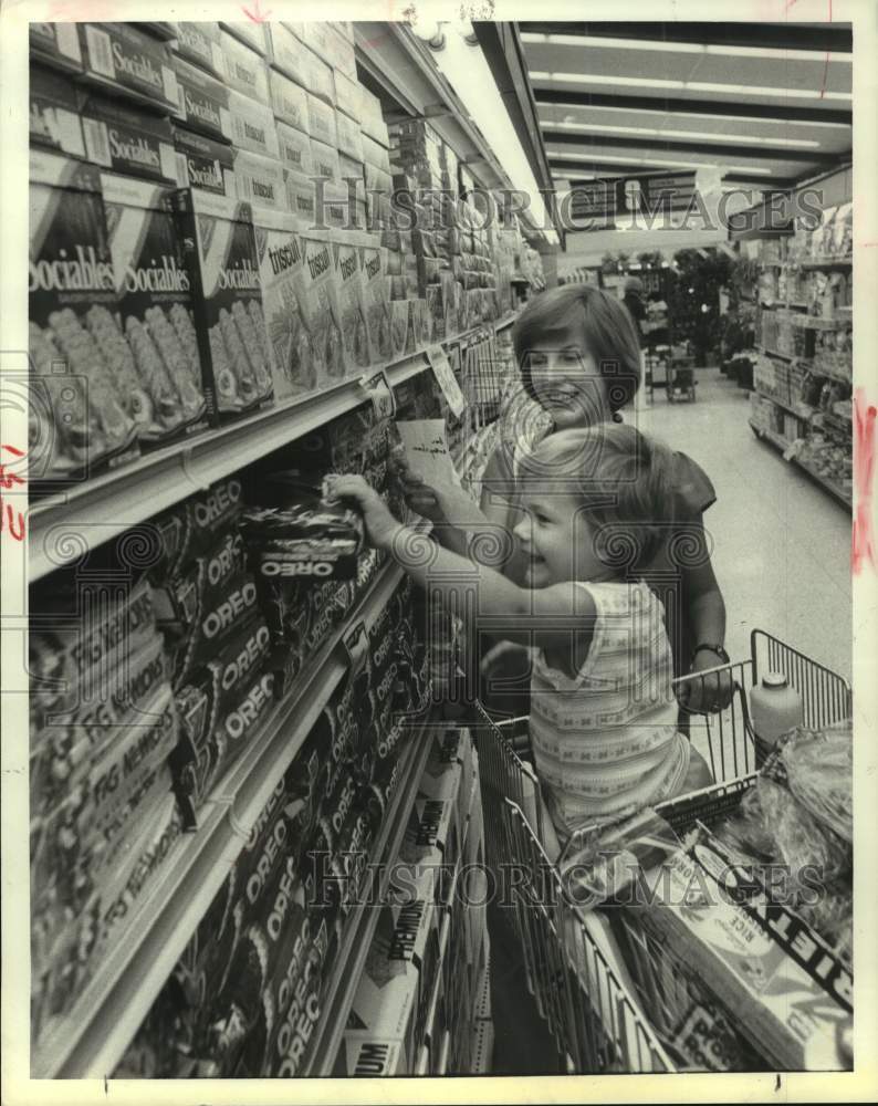 1979 Mother pushes grocery cart with her child in in supermarket - Historic Images