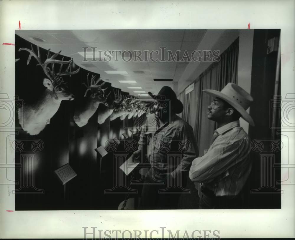 1991 Men view deer specimens at Houston Livestock Show &amp; Rodeo - Historic Images