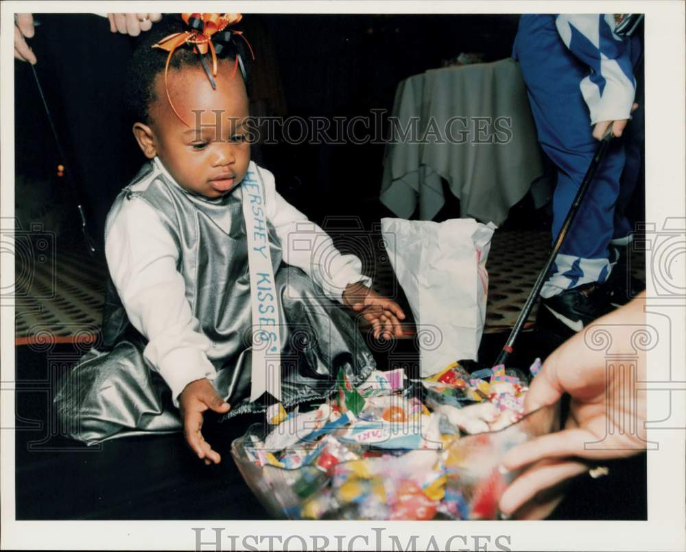 1994 Press Photo Shanae McDowell Reaches for Candy at Halloween Bash for Charity - Historic Images