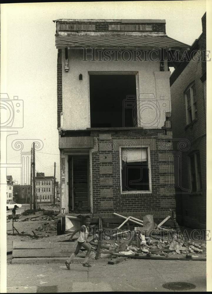 1981 Press Photo Child runs outside Atlantic City, New Jersey dilapidated Home- Historic Images