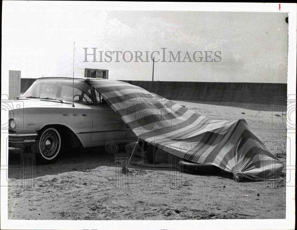 1963 Press Photo A beach visitor relaxes under a tent attached to a car - Historic Images