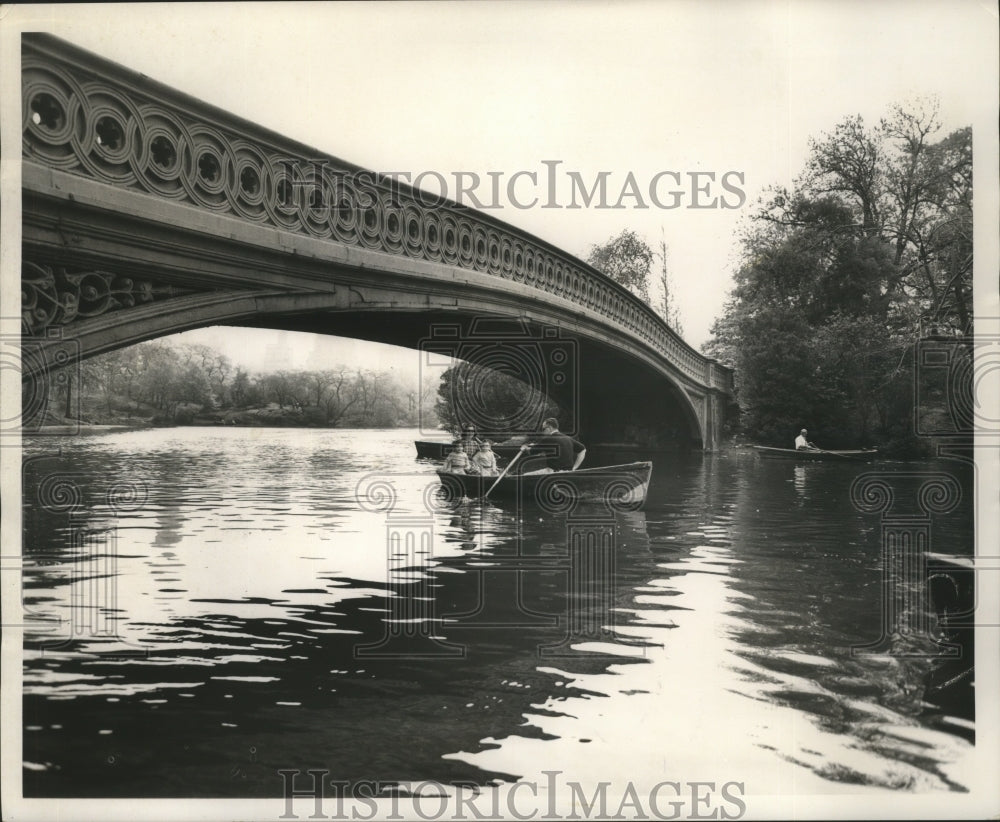 1962 Press Photo A family in a row boat ride under wooden bridge in NYC park - Historic Images