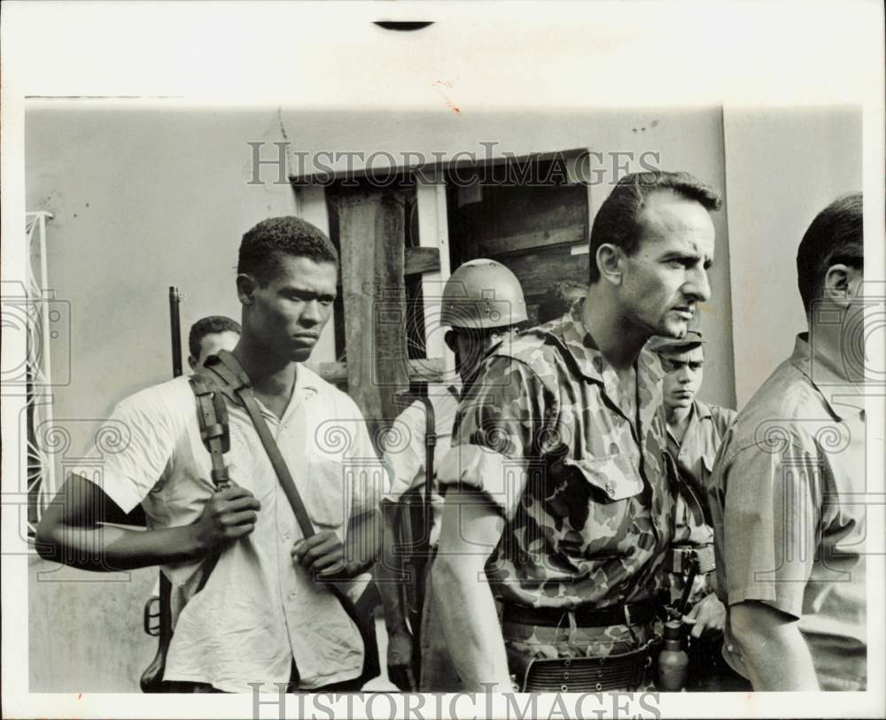 1965 Press Photo Armed guards walking with a man wearing camouflage clothing- Historic Images