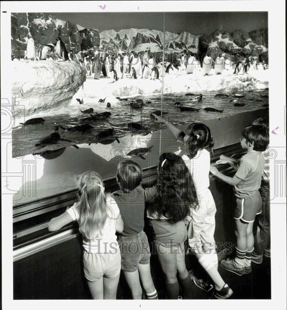 1984 Press Photo Children ride moving sidewalk as they watch penguins at exhibit- Historic Images