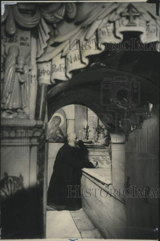 1971 A priest prays at a replica of Christ's tomb - Historic Images