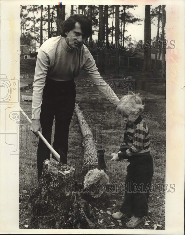 1976 Dr. George Panos and his son chopping a tree - Historic Images