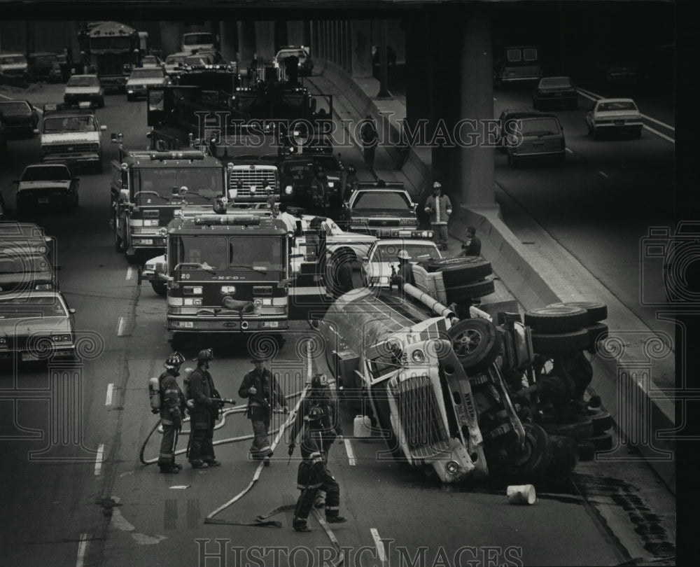 1991 Press Photo Firefighters watch on overturned truck at Marquette Interchange - Historic Images