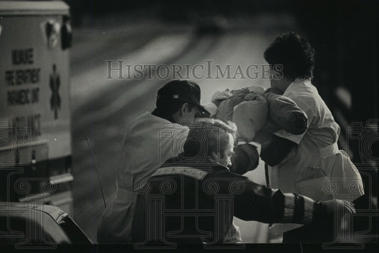 1988 Press Photo Paramedics & a firefighter rush a child to ambulance - Historic Images