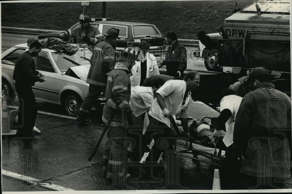 1991 Press Photo Woman Pinned Against Dept of Public Works Truck in Milwaukee - Historic Images