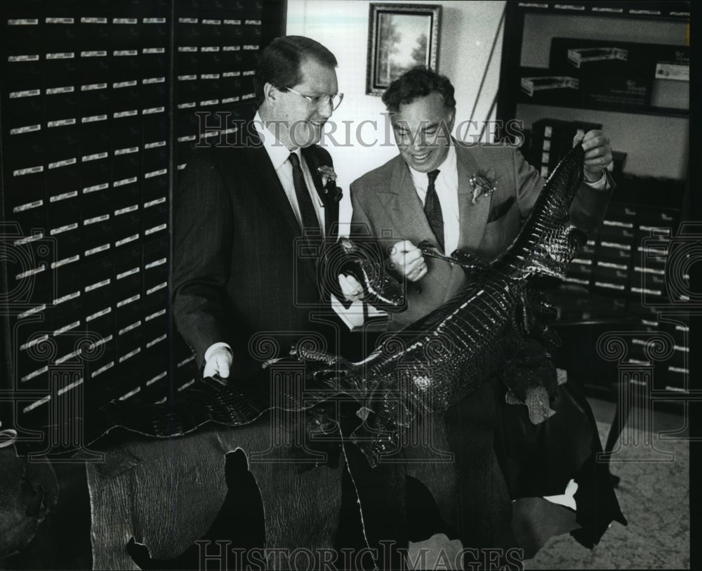 1990 Press Photo Patrick Philmon and Mr. Stollenwerk look over an alligator skin - Historic Images