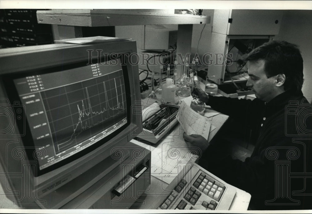 1991 Press Photo Scott J. Kahle checks data from a Biotronics Technologies - Historic Images