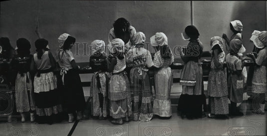 1989 Press Photo Girls in pioneer clothing line up to make jewelry from seeds - Historic Images