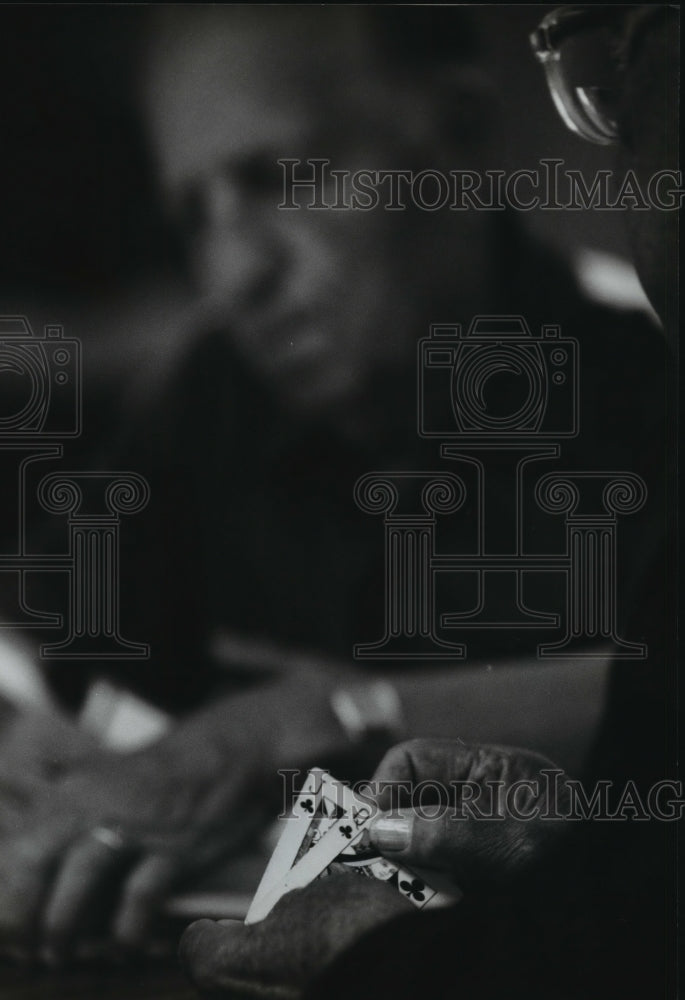 1994 Press Photo During a game of bridge one of the card players looks over hand - Historic Images