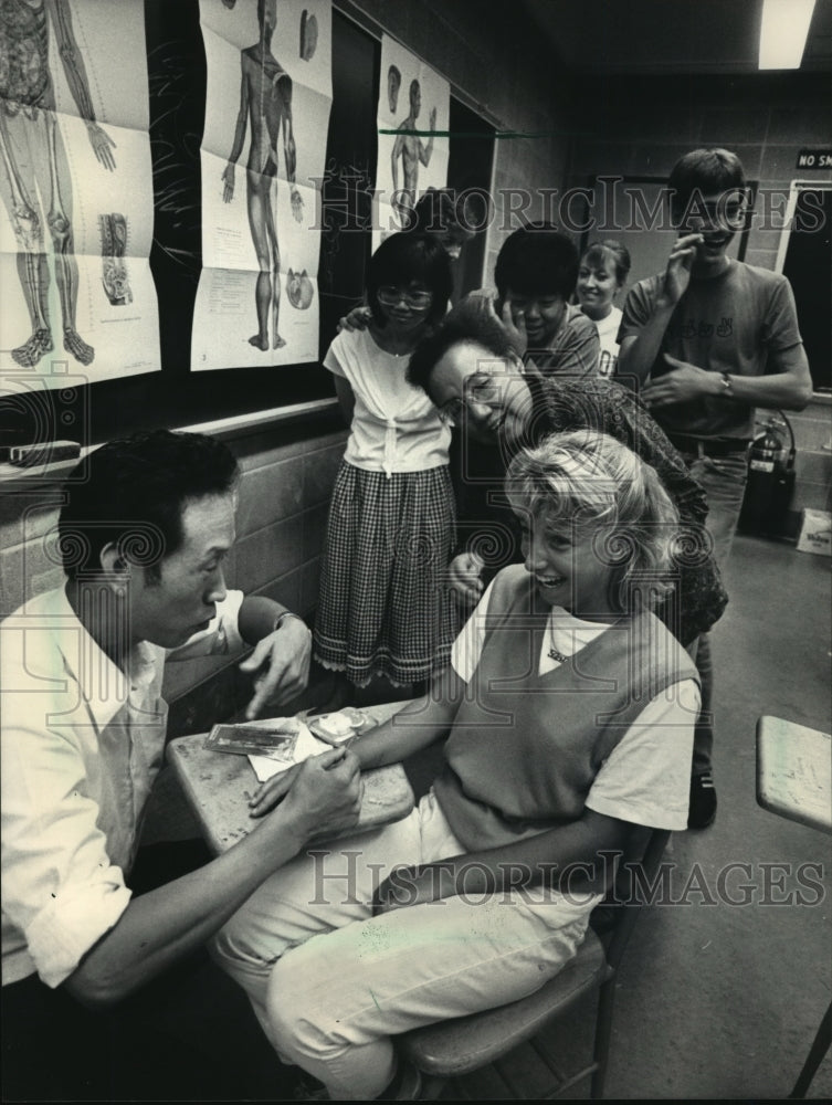 1986 Press Photo Tori Marian reacted as Huang Shao-Xun stuck a needle into arm - Historic Images