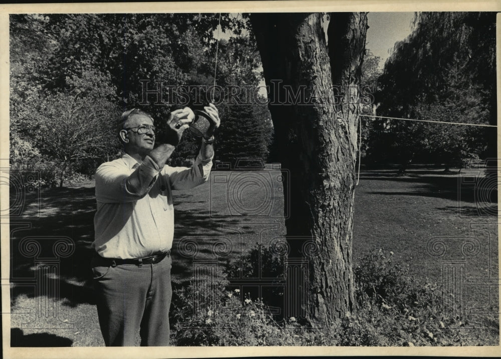 1985 Press Photo Mel Behling refilled a hanging bird feeder at his Glendale home - Historic Images