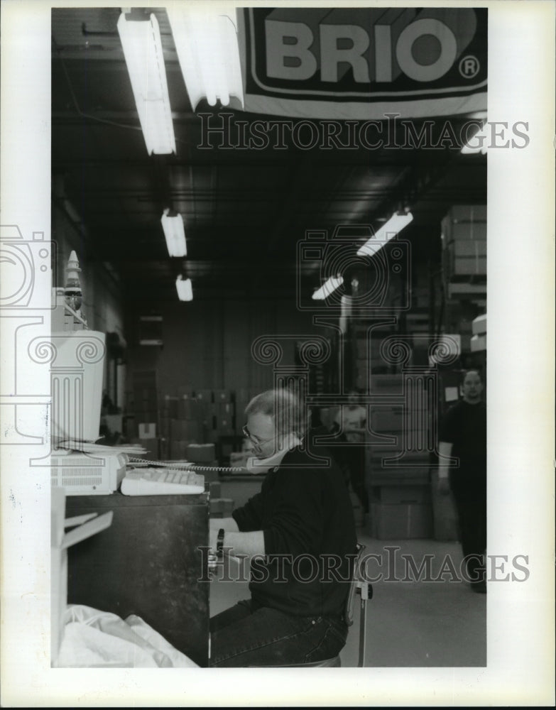 1995 Press Photo Warehouse manager Mike Denz talks on the phone as he works - Historic Images