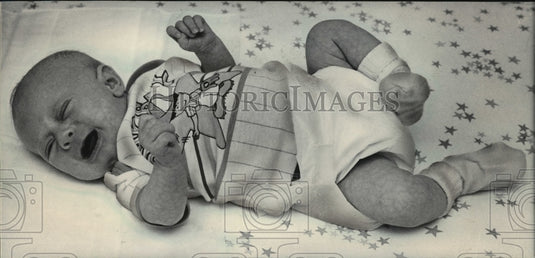 1984 Press Photo Knees pull up toward this baby's chest and tiny fingers - Historic Images