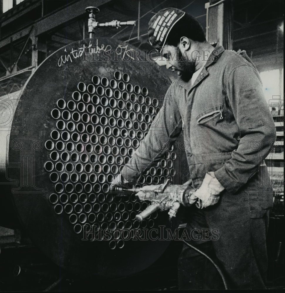 1975 Press Photo A workman rolled tubes into a shell and tube heat exchanger-Historic Images