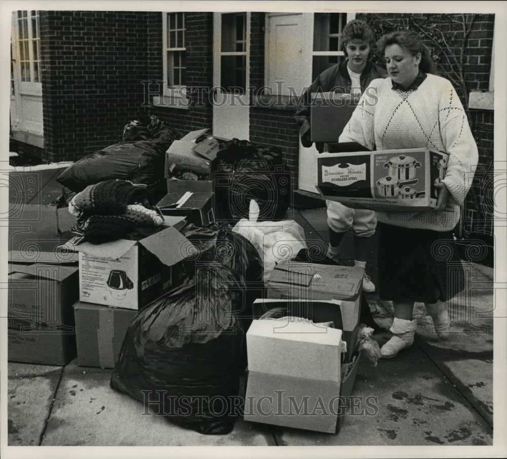 1988 Press Photo J. Carlock &amp; L. Krause organize clothing pile at Caroll College - Historic Images